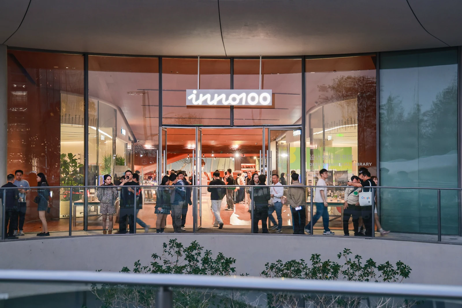 INNO100 illuminated storefront with visitors gathered inside in the evening